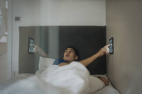 Boy adjusting temperature of bedroom through digital tablet at modern home - MASF42830