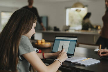 Vorpubertäres Mädchen benutzt einen Laptop, während sie zu Hause sitzt - MASF42873