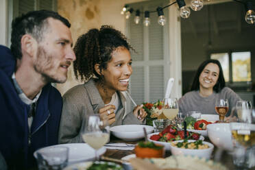 Lächelnde Frau sitzt mit Freunden am Esstisch für eine Dinnerparty - MASF42917