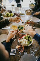 Männliche Freunde servieren Essen am Esstisch während einer Dinnerparty im Innenhof - MASF42924