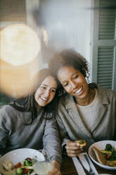 Lächelnd junge weibliche Freunde sitzen am Esstisch im Innenhof für Abendessen Partei - MASF42927