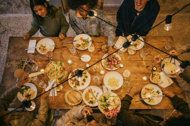 High angle view of multiracial friends sitting at illuminated dining table during dinner party - MASF42943