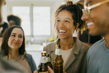 Glücklicher junger Mann und Frauen mit Bierflaschen auf einer Party - MASF42953