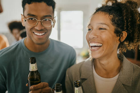 Fröhlicher junger Mann und Frau mit Bierflaschen in der Küche - MASF42954