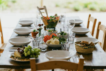 Esstisch mit Schüsseln und Tellern auf der Terrasse im Hinterhof - MASF42967