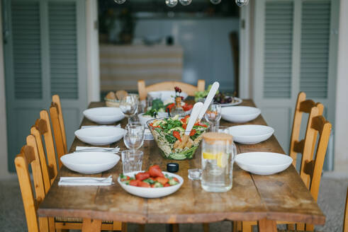 Esstisch mit Stühlen und Abendessen auf der Terrasse im Hinterhof - MASF42969