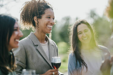 Happy multiracial female friends standing at backyard during party - MASF42970