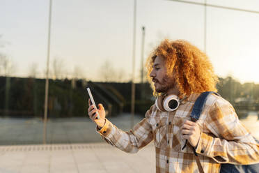 Mann benutzt Smartphone in der Nähe eines Glasgebäudes - JCCMF11146