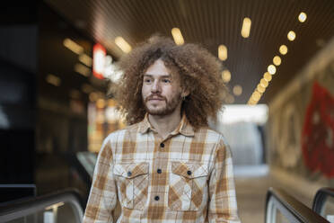 Lächelnder Mann mit lockigem Haar in der U-Bahn stehend - JCCMF11167