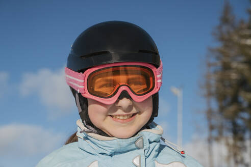 Smiling girl wearing ski goggles at resort - OSF02393