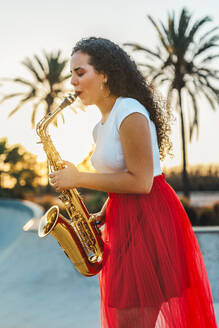 Frau mit lockigem Haar übt Saxophon im Skatepark - ASNF00005
