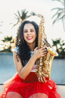 Glückliche Frau mit goldfarbenem Saxophon im Skatepark - ASNF00008