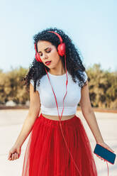 Frau hört Musik über kabelgebundene Kopfhörer in einem Skatepark - ASNF00012