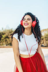 Unbekümmerte Frau, die im Park über kabelgebundene Kopfhörer Musik hört - ASNF00013