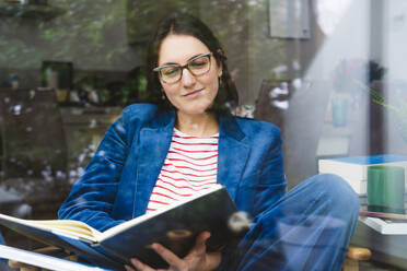 Smiling businesswoman examining documents at home office - IHF01886