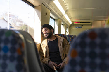 Young man napping in subway train - VRAF00387