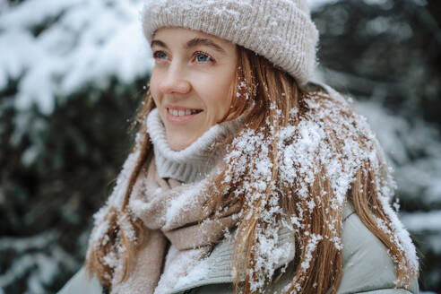 Lächelnde Frau mit Schnee auf braunem Haar im Winter - NLAF00252