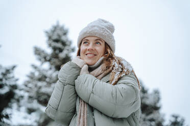 Lächelnde Frau mit Jacke und Tagträumen im Winter - NLAF00254