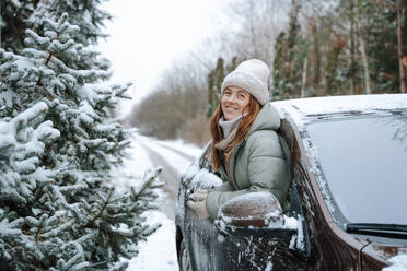 Smiling woman leaning out of car window - NLAF00260