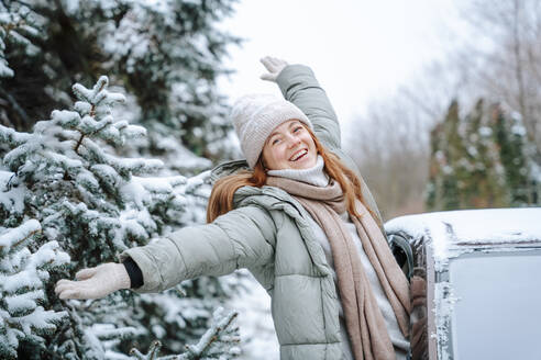 Carefree woman with arms outstretched leaning out of car window - NLAF00262