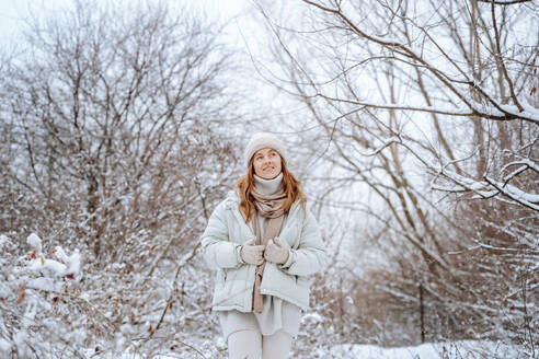 Lächelnde Frau inmitten von gefrorenen Bäumen im Winter - NLAF00263