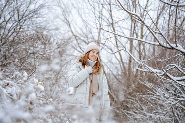 Lächelnde Frau verbringt ihre Freizeit inmitten gefrorener Bäume im Winter - NLAF00265