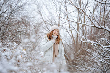 Smiling woman spending leisure time amidst frozen trees in winter - NLAF00265