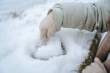 Frau macht Herzform auf Schnee im Winter - NLAF00269