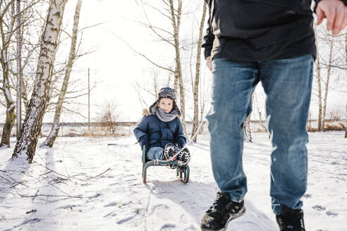 Father pulling boy sitting on sled in winter - NLAF00284