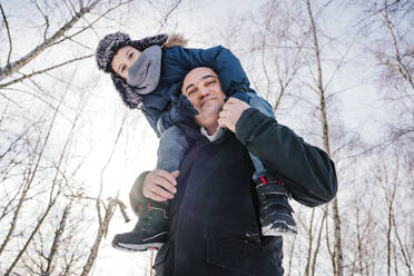 Smiling father carrying son on shoulders in winter - NLAF00290