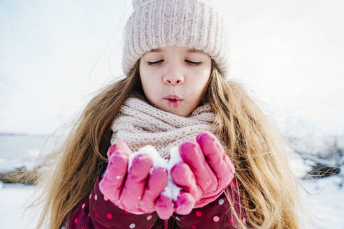 Mädchen in warmer Kleidung sammelt Schnee in den Händen - NLAF00296