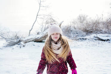 Lächelndes Mädchen mit geschlossenen Augen auf Schnee im Winter stehend - NLAF00297