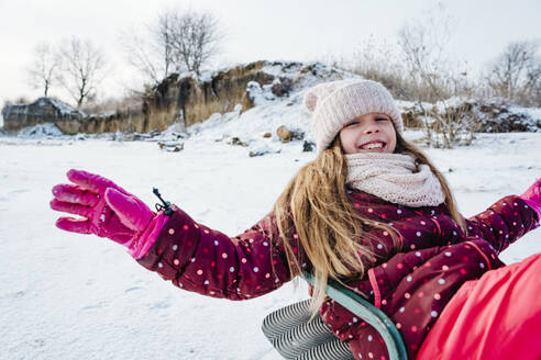 Cheerful girl enjoying sled ride on snow in winter - NLAF00298