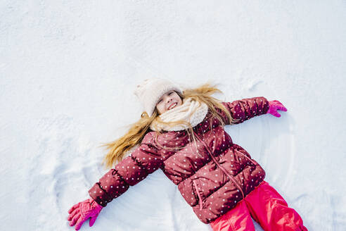 Unbekümmertes Mädchen im Schnee liegend im Winter - NLAF00300