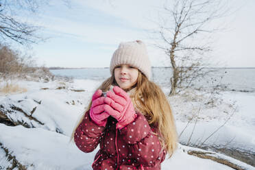 Mädchen hält Teetasse auf Schnee im Winter - NLAF00302