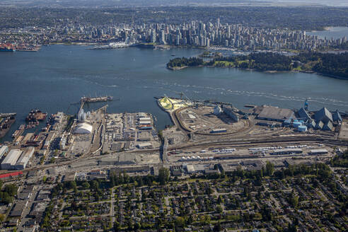 Kanada, Britisch-Kolumbien, Vancouver, Luftaufnahme der industriellen Küstenlinie mit der Innenstadt in der Ferne - NGF00833