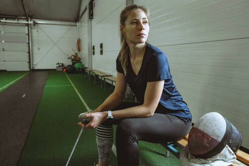 Woman in active wear sitting on bench in gym - YHF00104