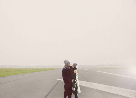 Paar umarmt sich auf der Landebahn des Flughafens - FSIF06844