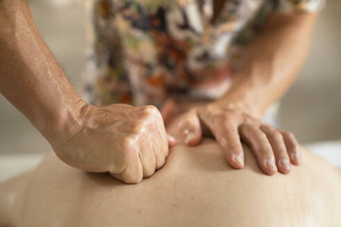 Nahaufnahme Massagetherapeutin massiert Rücken eines Mannes mit der Faust - FSIF06875