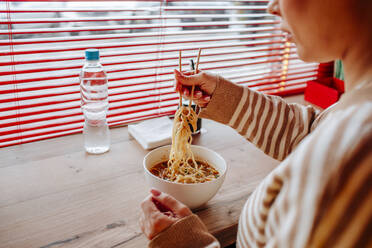 Woman eating ramen using chopsticks at cafe - MDOF01819