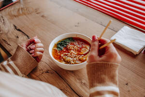 Frau mit Schüssel frischer Ramen-Nudeln auf dem Tisch im Restaurant - MDOF01825