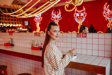 Woman with ramen noodles bowl on tiled table at restaurant - MDOF01827