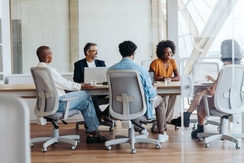 Business team discussing and planning a project during a meeting in a modern boardroom. Collaboration, teamwork, and creativity are on display as the team happily shares ideas in a startup workplace. - JLPSF31138