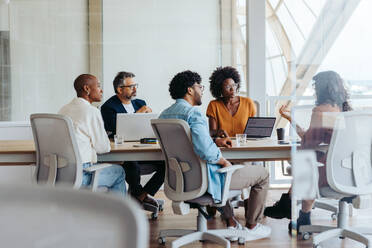 Eine kreative Gruppe von Fachleuten arbeitet in einem modernen Büro zusammen und führt ein Brainstorming durch. Sowohl Männer als auch Frauen beteiligen sich aktiv an einer dynamischen Diskussion und demonstrieren Teamwork und Kreativität. - JLPSF31140