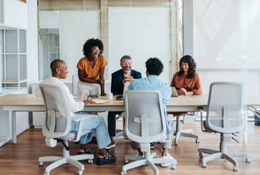 Business people in a boardroom engage in a productive discussion, collaborating on a project. Team members, both men and women, share ideas and plan together. A creative workplace environment showcases successful teamwork. - JLPSF31141