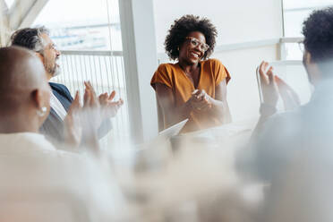 Team of business people applauding and celebrating successful teamwork and creativity during a meeting. Smiling and positive, they work together towards success in a startup workplace. - JLPSF31155