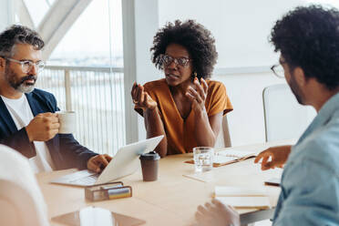 Verschiedene Fachleute führen in einem Sitzungssaal eine kreative, produktive Diskussion. Teamwork und Zusammenarbeit sind in dieser modernen Büroumgebung der Schlüssel. - JLPSF31165