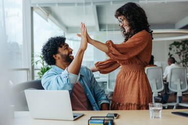 Glückliche Geschäftsleute, die ein erfolgreiches Projekt mit einem High Five im Büro feiern. Dieses vielfältige Team ist kreativ und motiviert und verkörpert den Geist eines erfolgreichen Start-ups. - JLPSF31184