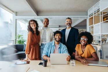 Ein erfolgreiches Unternehmerteam, das in einem Büro zusammenarbeitet. Sie sind glücklich, lächeln und schauen in die Kamera und repräsentieren ihr florierendes Start-up-Unternehmen. - JLPSF31187