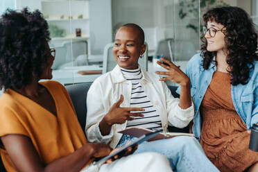 Female entrepreneurs discussing ideas in a modern office. Group of business women displaying teamwork and creativity. Happy colleagues working together in a dynamic workplace. - JLPSF31196